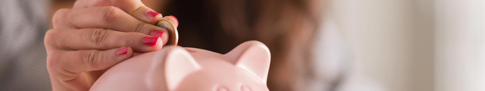 Woman putting coin in piggy bank, inside.