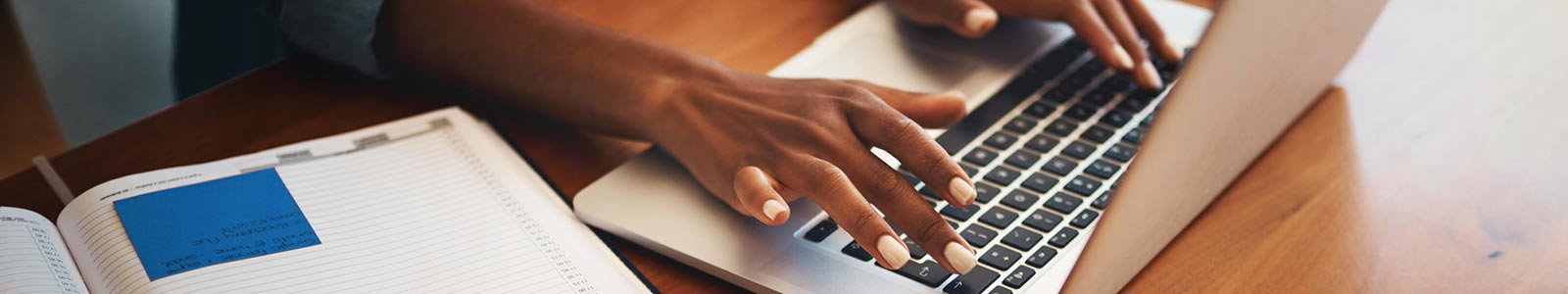 Woman typing on laptop while sitting inside at office.