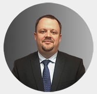 Picture of a man standing wearing a suit and smiling. 
